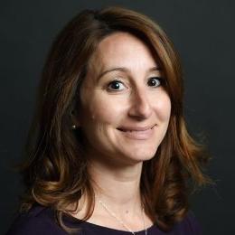 Lady with dark brown shoulder length hair with black top in front of black background