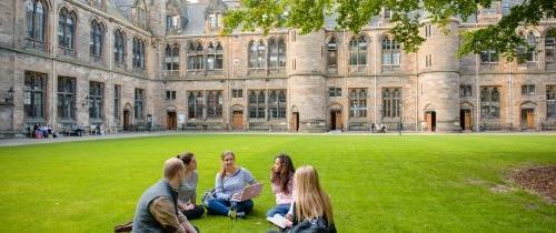 Group of Centre students sitting on lawn in Glasgow in front of historic building